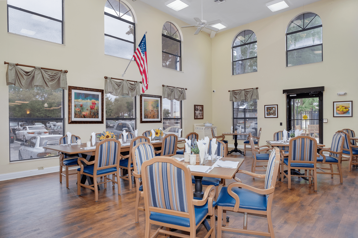 A neatly arranged dining area with multiple tables and chairs, adorned with framed art and an American flag.