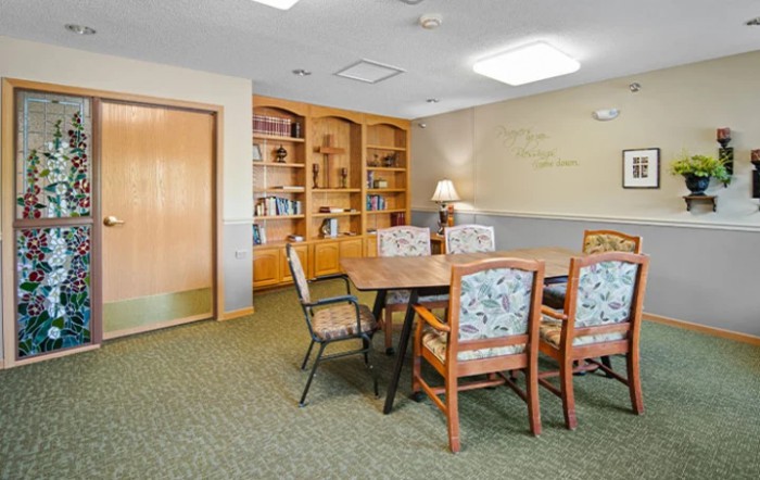 A well-lit meeting room with a conference table, several chairs, and built-in bookshelves.