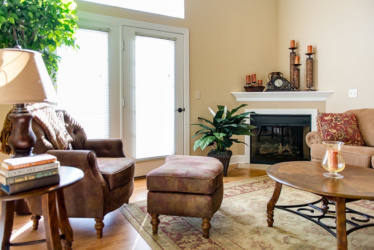A cozy living room featuring a fireplace, comfortable chairs with an ottoman, and stylish home decor.