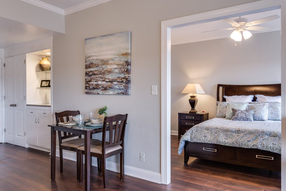 A modern apartment interior with a small dining table near the entrance to a cozy bedroom.