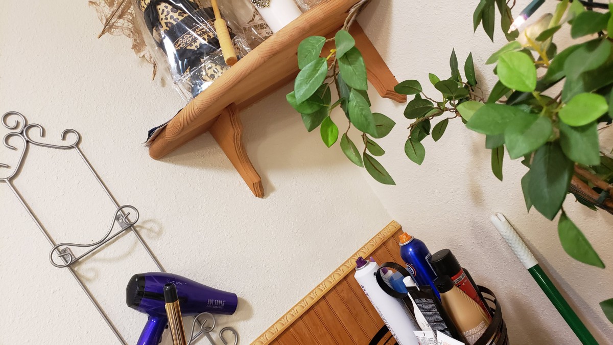 A cozy corner with a wall-mounted shelf, featuring plants and various tools.