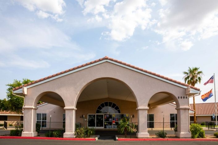 A building with an arched entrance and a sunny sky in the background.