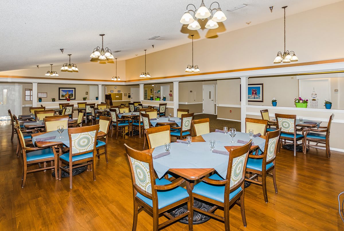 A spacious dining area with neatly arranged tables and chairs, decorated with elegant lighting fixtures.