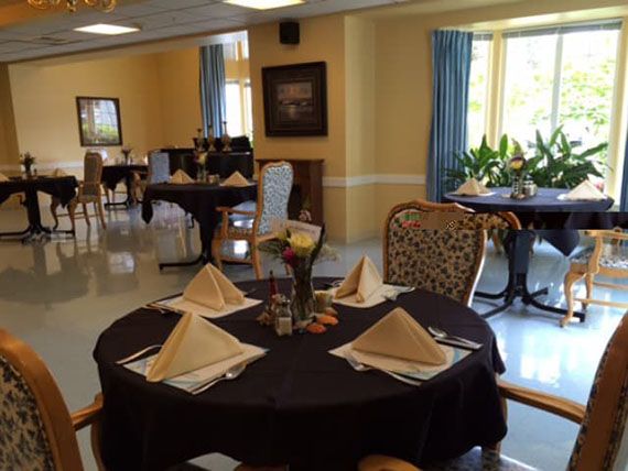 A dining room with elegantly set tables, featuring folded napkins and comfortable chairs.