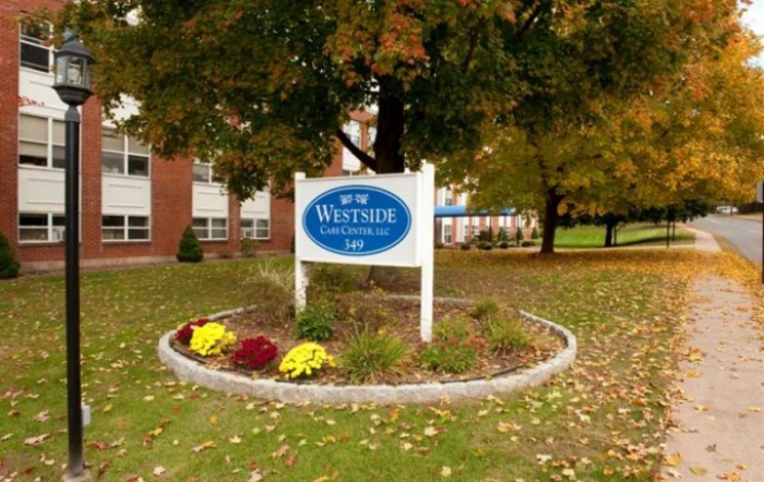 A school sign surrounded by autumn trees and landscaping.