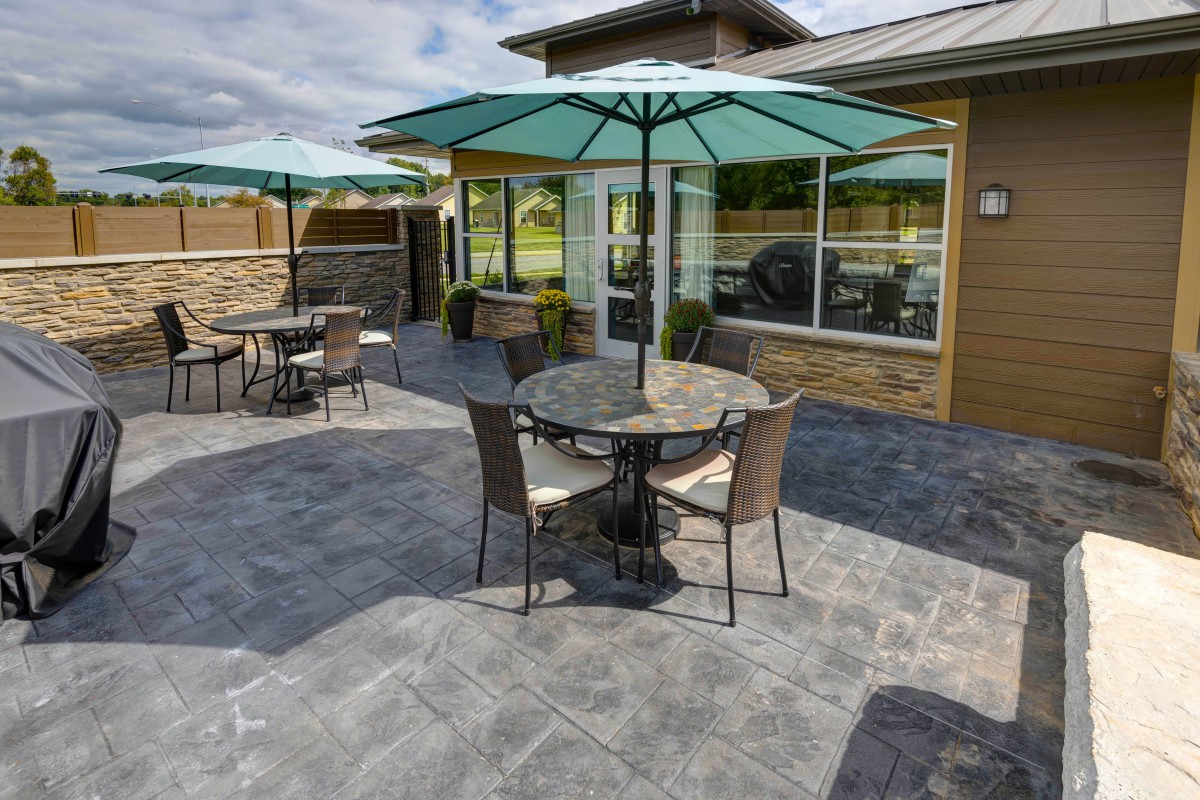 A sunny outdoor patio with tables and chairs under umbrellas.