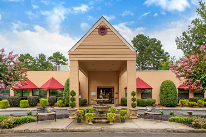 The front entrance of a hotel with landscaped greenery and a prominent architectural design.