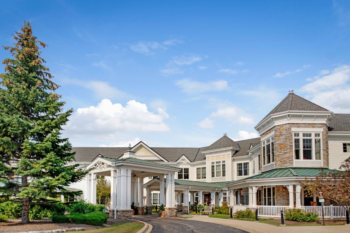 A large, elegant building with a grand entrance set against a blue sky with scattered clouds.