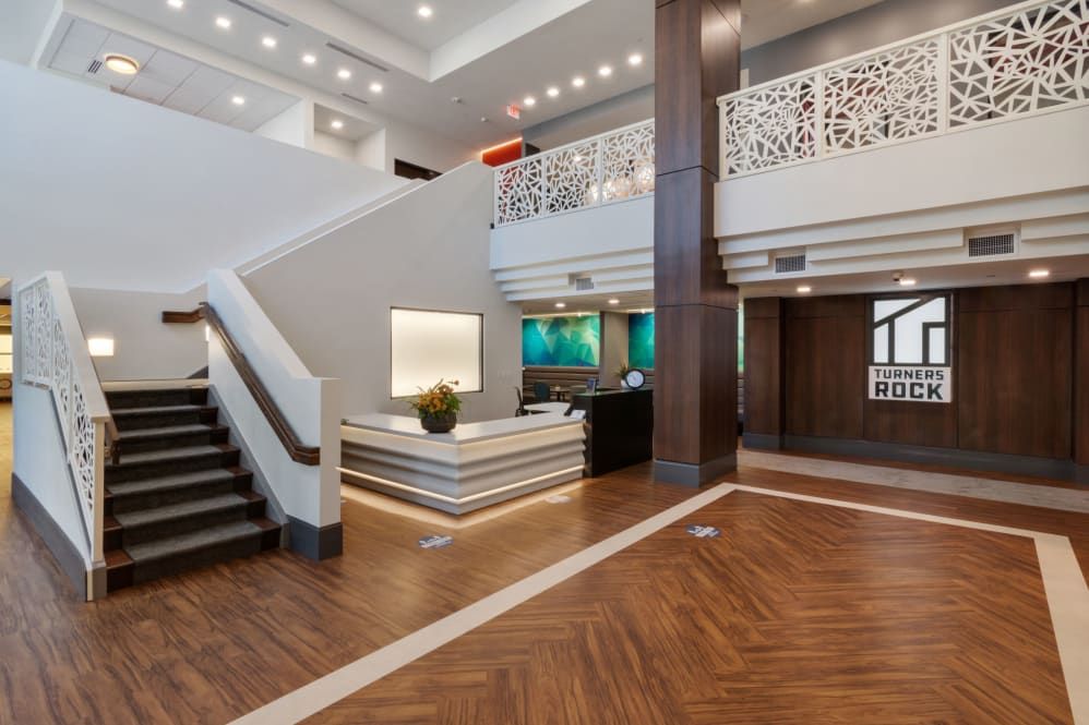 A modern hotel lobby with a reception desk, stylish lighting, and elegant wood flooring.