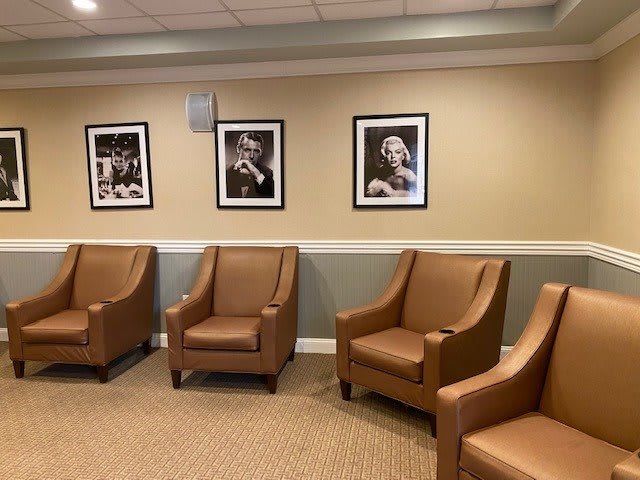 A cozy waiting room with brown leather chairs and black-and-white framed photographs on the wall.