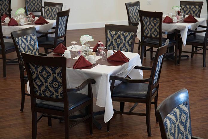 A restaurant dining area with elegantly set tables, featuring white tablecloths and red napkins.