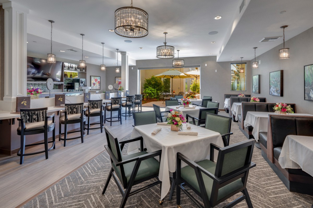 A modern and elegant dining area with neatly arranged tables and chairs, featuring stylish lighting fixtures.