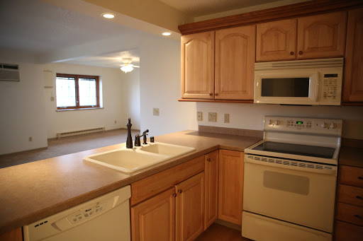 A modern kitchen featuring wooden cabinets, stainless steel appliances, and a spacious countertop.