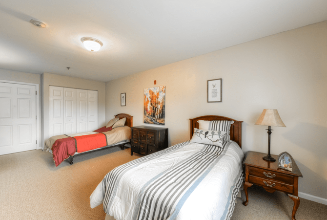 A cozy bedroom featuring twin beds with striped bedding, a dresser, and decorative elements.