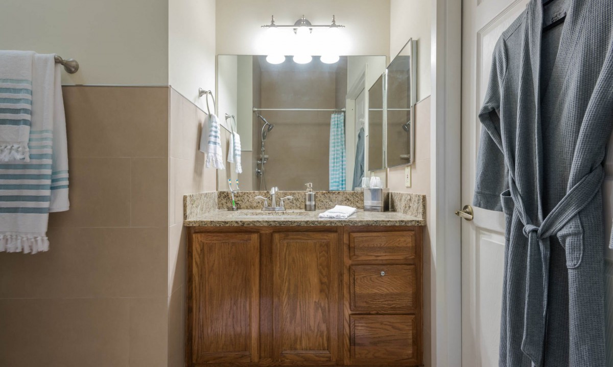A bathroom with a wooden vanity, large mirror, and towel racks.