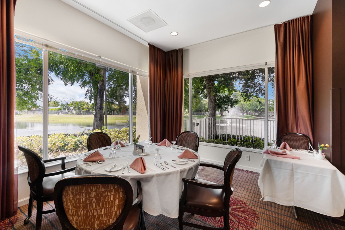 A cozy dining area with a round table and chairs, featuring large windows that offer a scenic outdoor view.