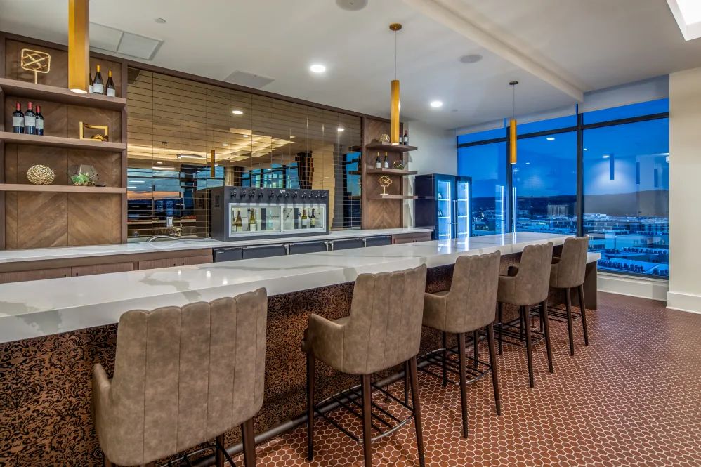 A modern bar interior with a long countertop and comfortable seating.