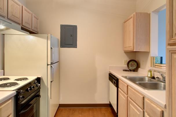 A compact apartment kitchen with modern appliances and wooden cabinets.