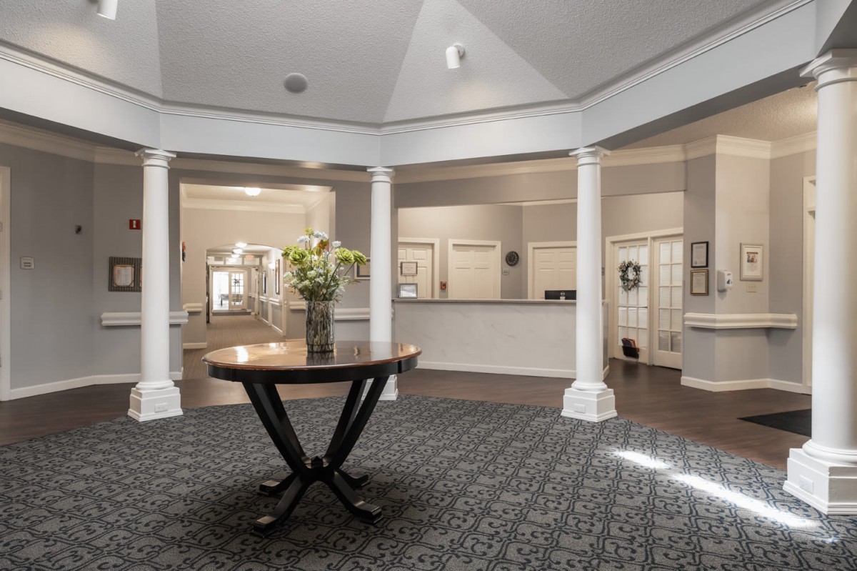Bright and elegant lobby with decorative columns and a central table adorned with flowers.