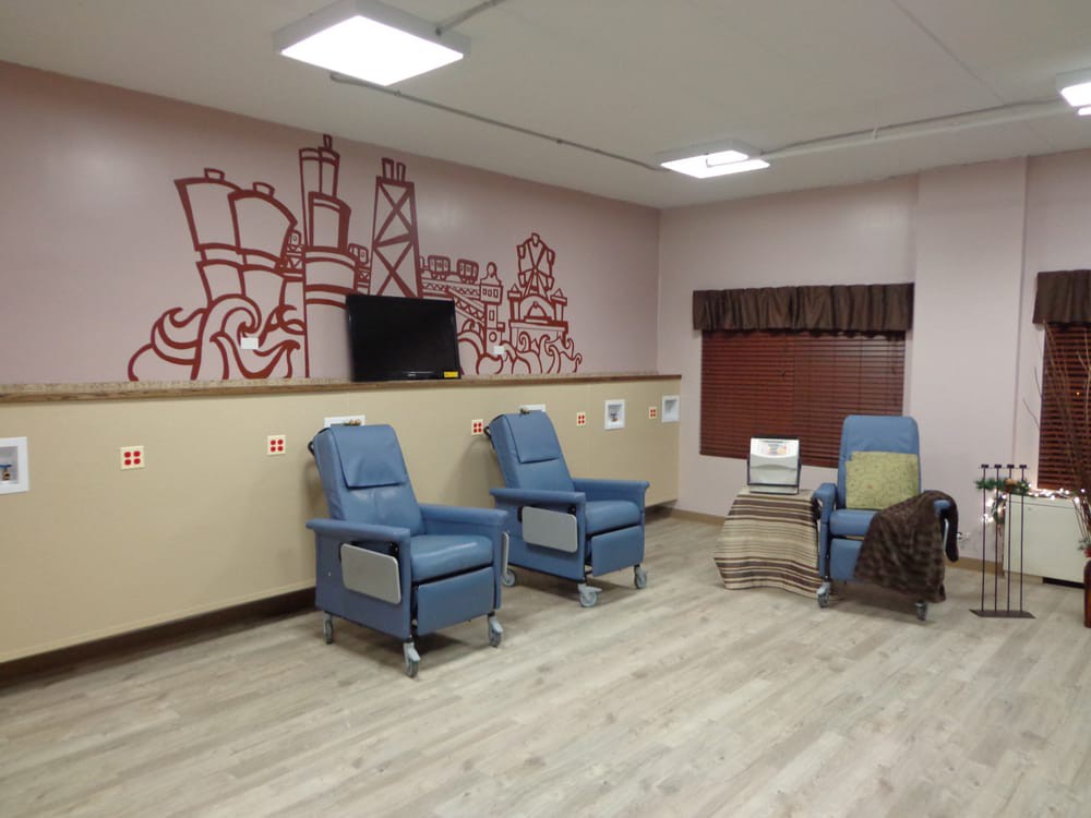 A waiting room with blue chairs, a television, and decorative wall art.
