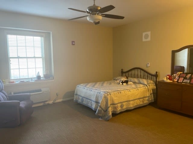 A cozy bedroom with a bed, ceiling fan, and window.