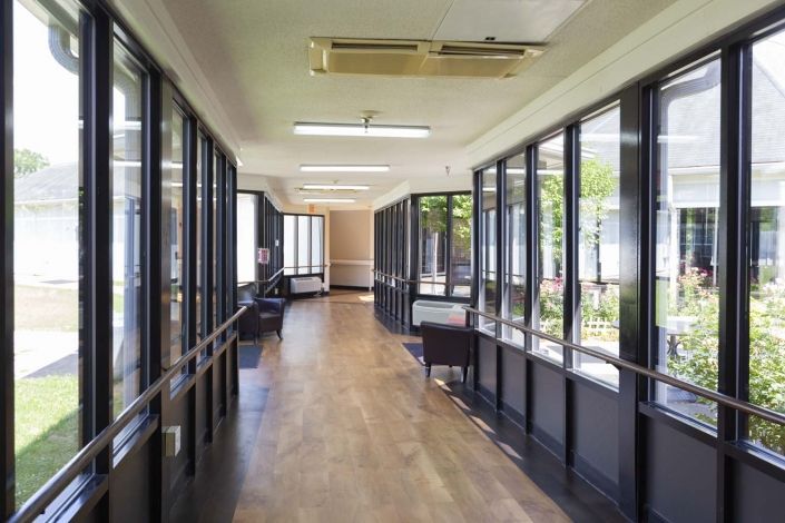 A bright, modern hallway with wooden flooring and large windows.