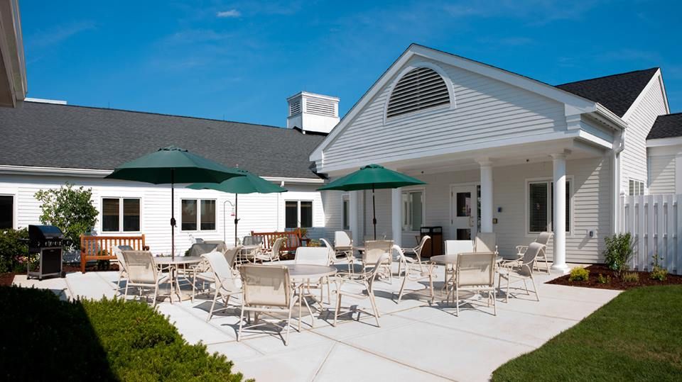 A sunny patio with chairs and umbrellas outside a building.