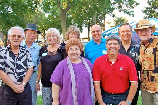 A group of adults posing for a photo outdoors in a park setting.