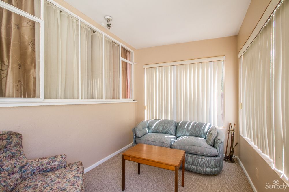 A cozy living room with a sofa, coffee table, and window blinds.