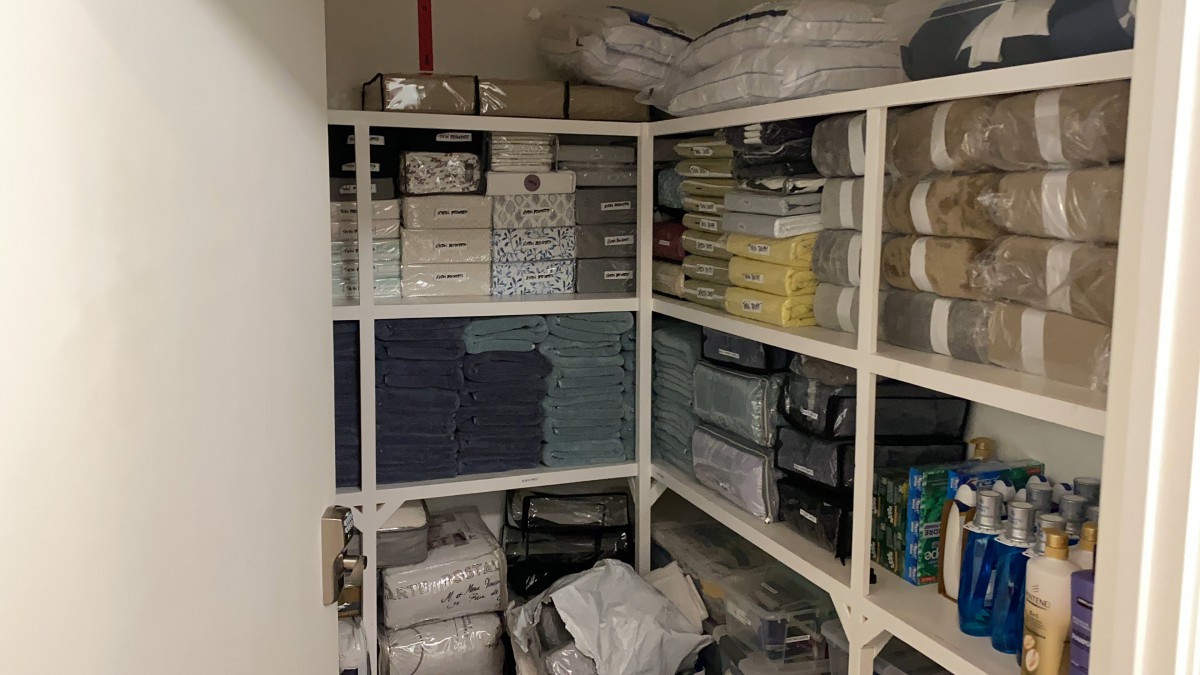 A well-organized closet with neatly stacked linens and textiles on shelves.