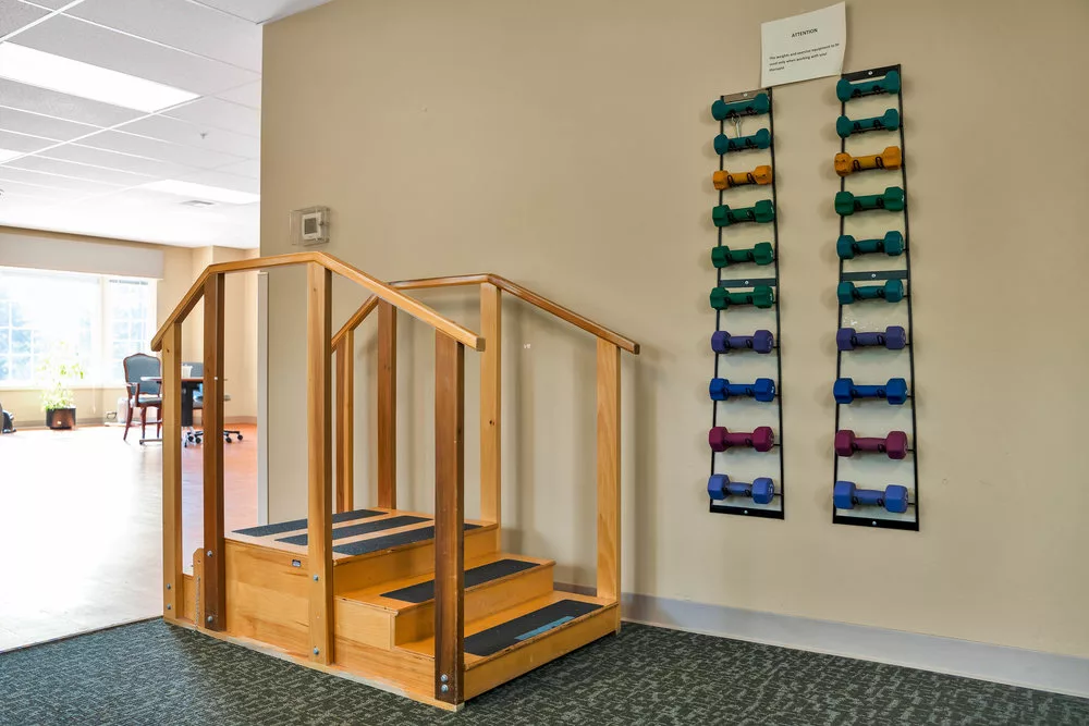 A physical therapy room with stairs and dumbbells for rehabilitation exercises.