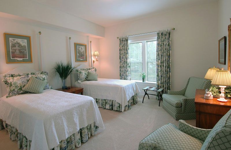 A cozy bedroom featuring twin beds with green accents and ample natural light.
