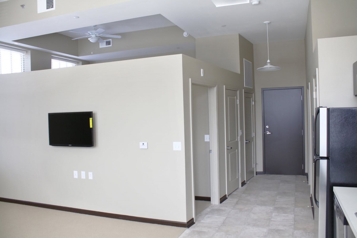 A modern apartment interior with a mounted television and multiple doorways.