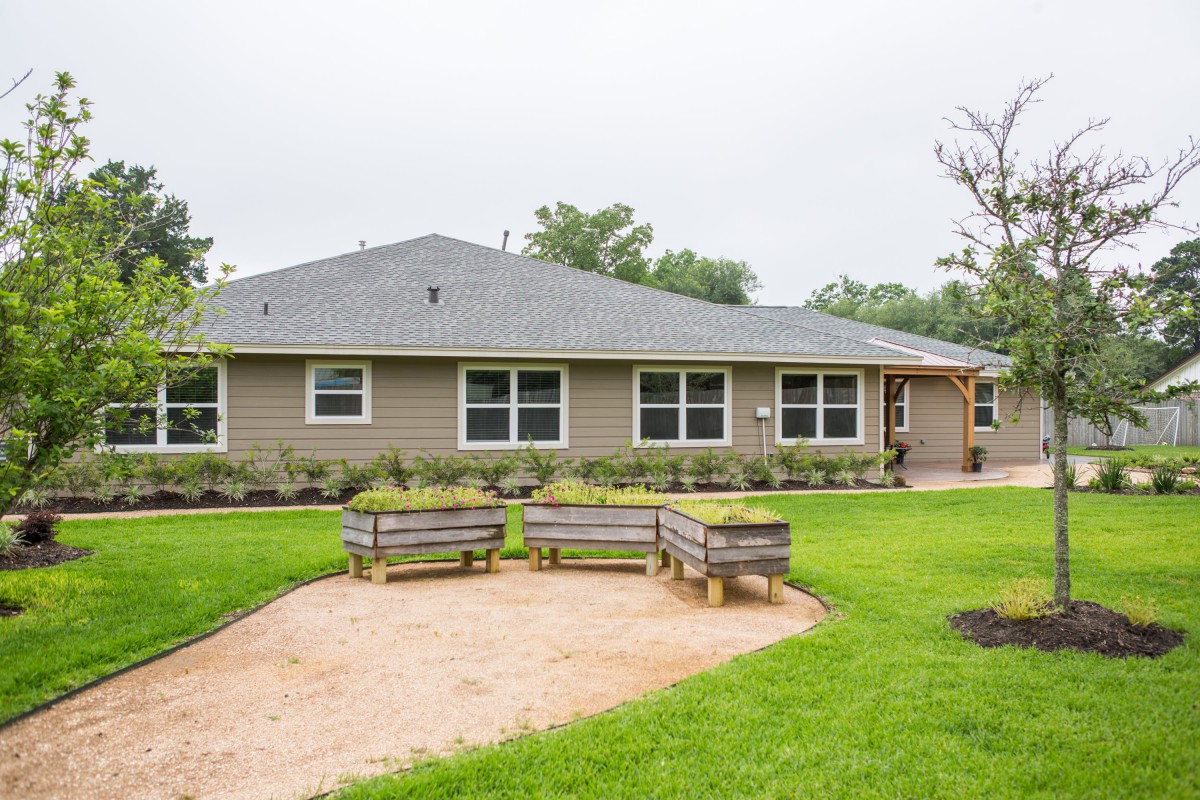 A suburban house with a well-maintained backyard featuring benches and lush greenery.