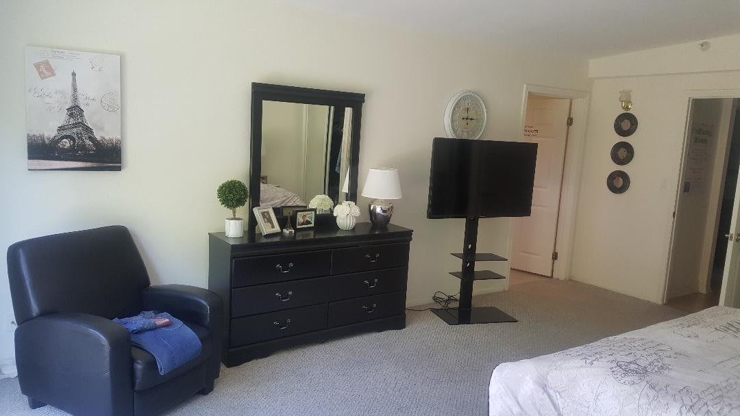 A cozy bedroom with a dresser, mirror, and TV setup.
