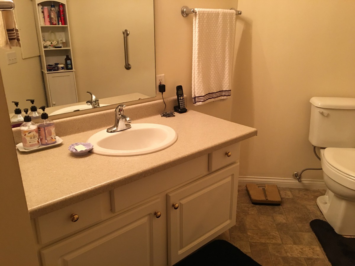 A clean and well-organized bathroom with a vanity, sink, mirror, and towel rack.