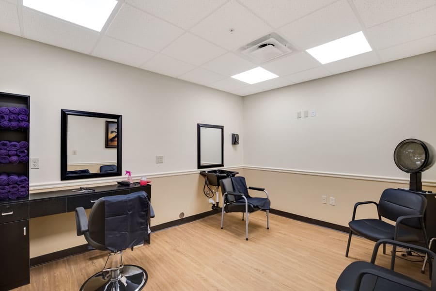 An empty hair salon with styling chairs and mirrors.