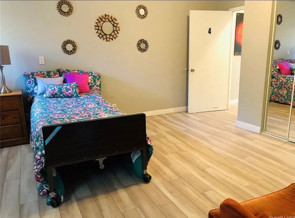A cozy bedroom with colorful bedding and stylish decor on a hardwood floor.