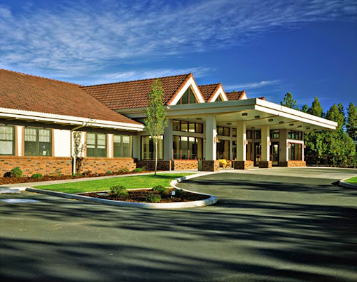 A welcoming entrance of a hospitality building, surrounded by well-maintained landscaping under a clear blue sky.