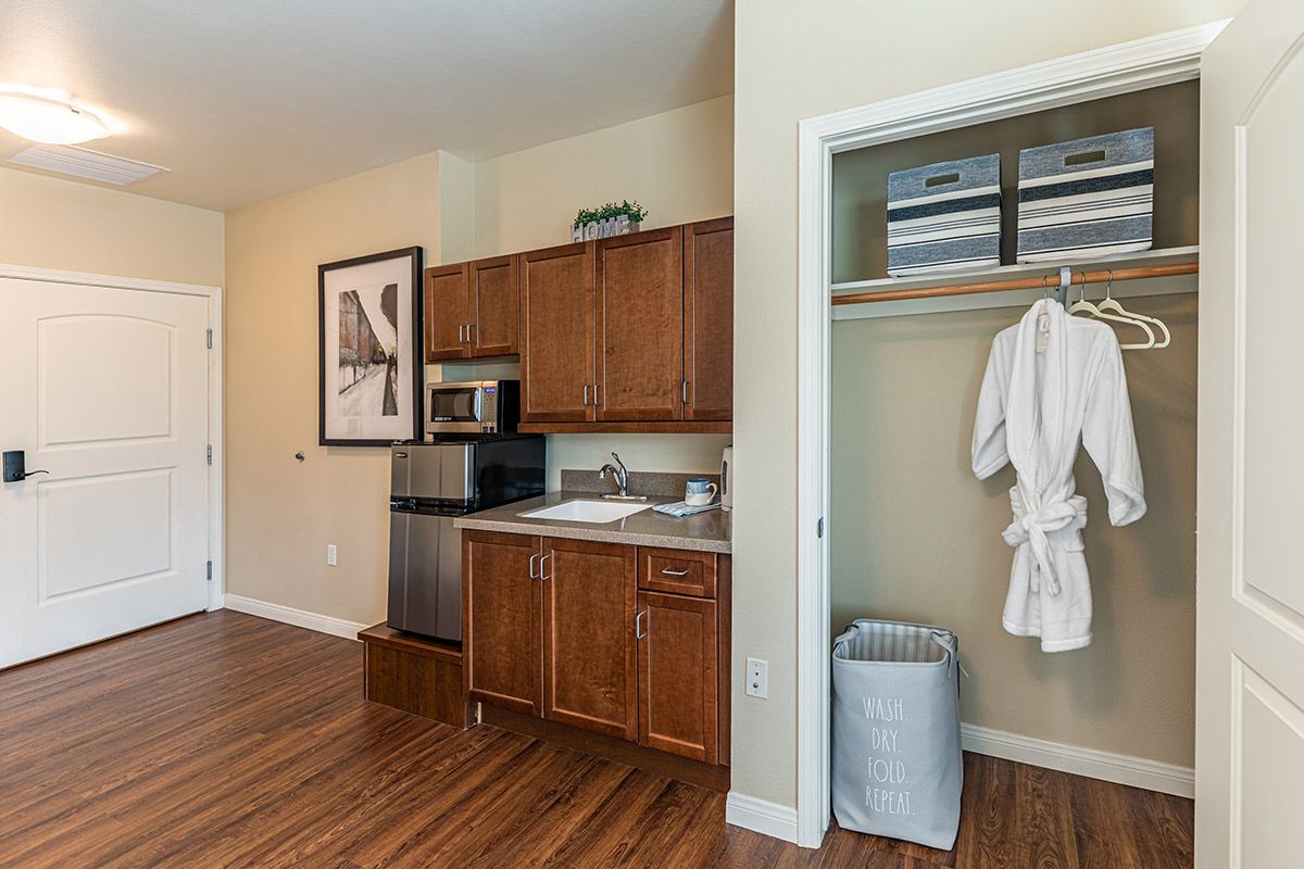 Hotel room with a kitchenette and closet featuring a robe.