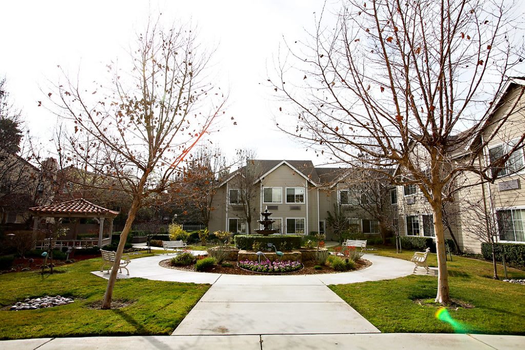 A view of an apartment complex with a landscaped walkway and bare trees.