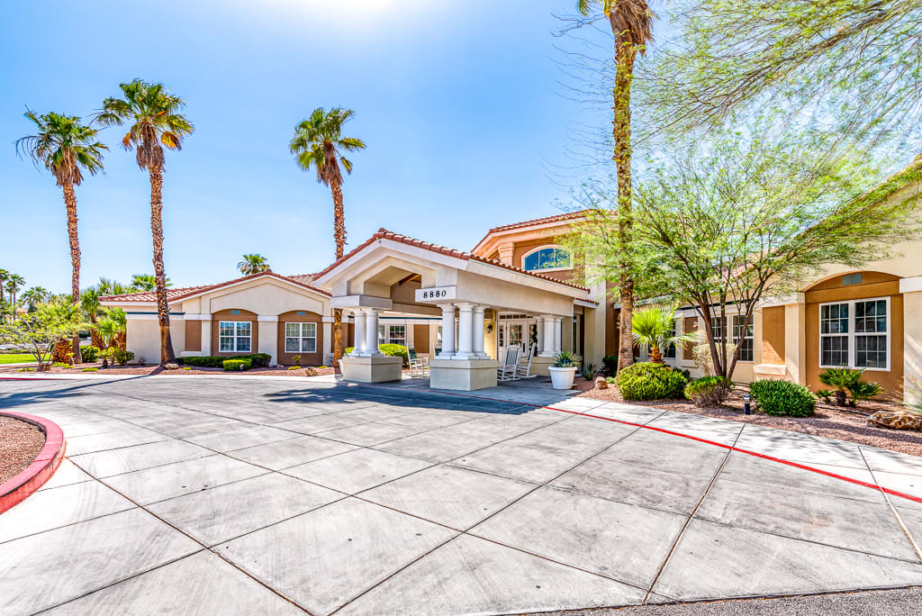 A sunny day view of a building entrance surrounded by palm trees.