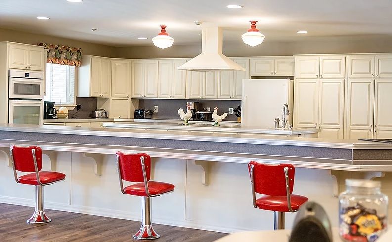A modern kitchen with red bar stools and white cabinetry.