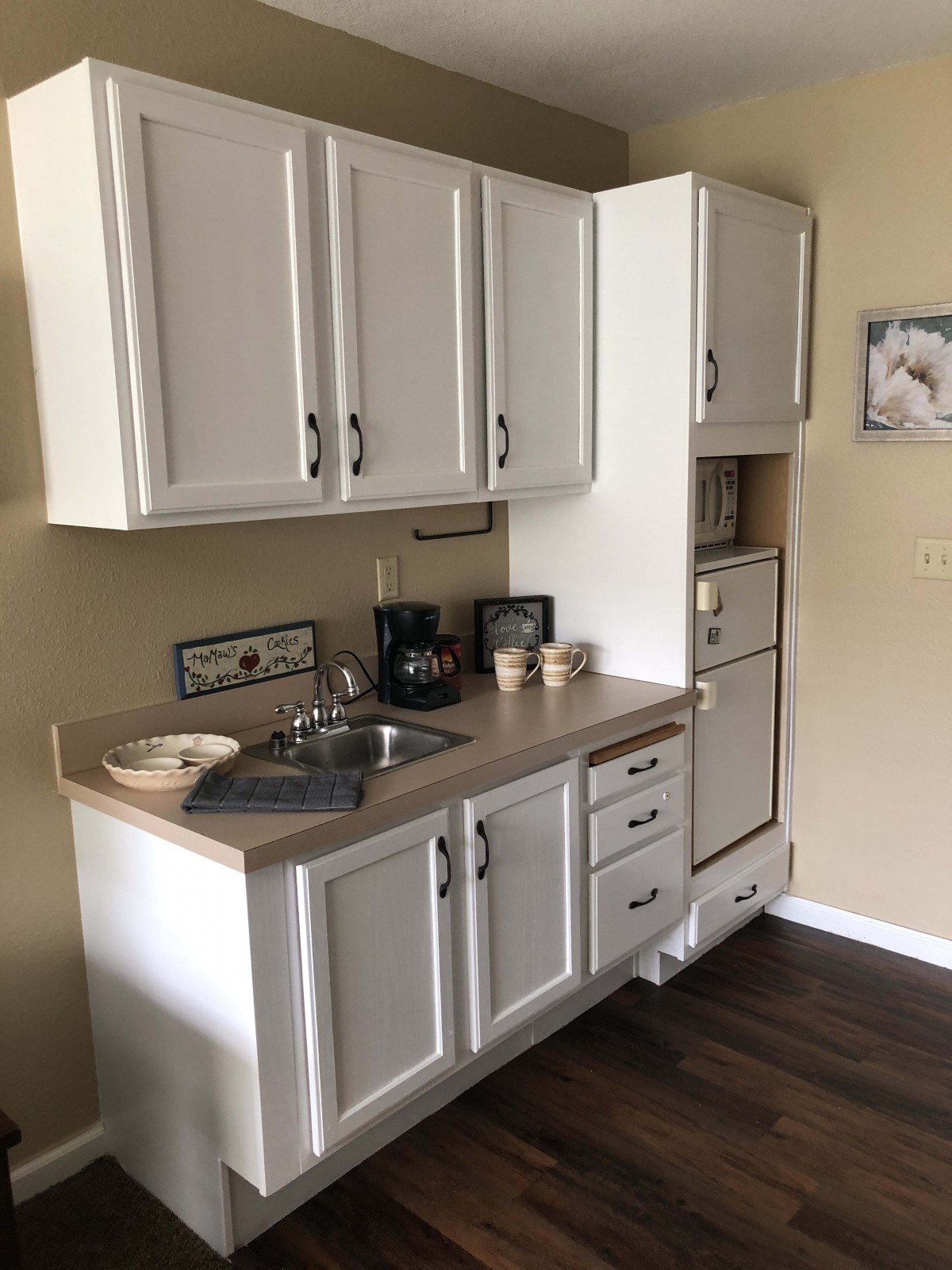 A compact kitchen with white cabinets, a sink, and appliances.