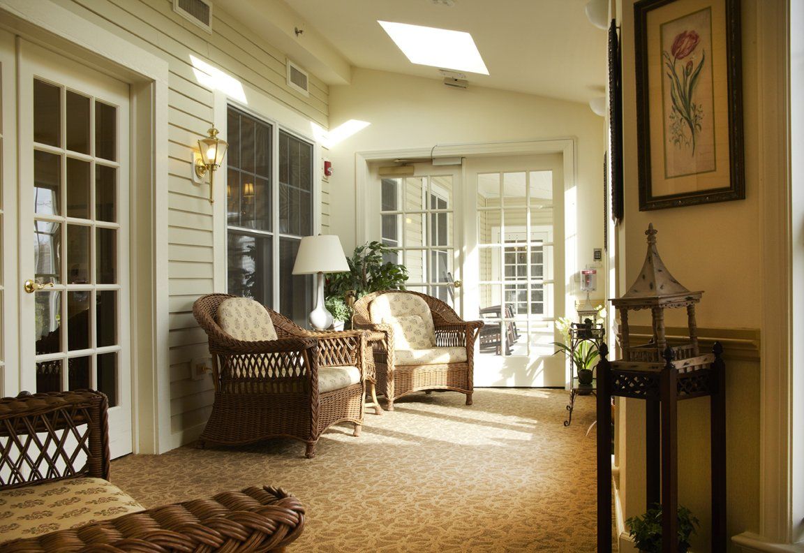 A cozy sunlit living area with wicker chairs and large windows.
