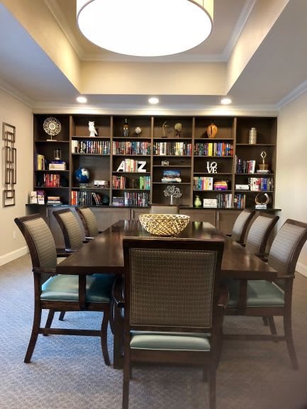 A well-organized conference room featuring a large table surrounded by chairs, with bookshelves filled with various items in the background.