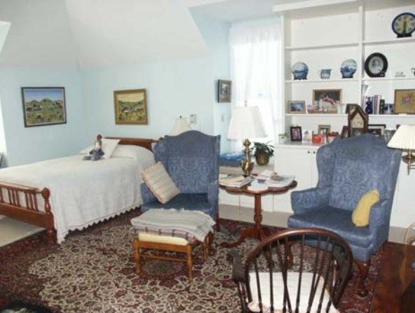 A cozy living area with a bed, blue chairs, and decorative items.