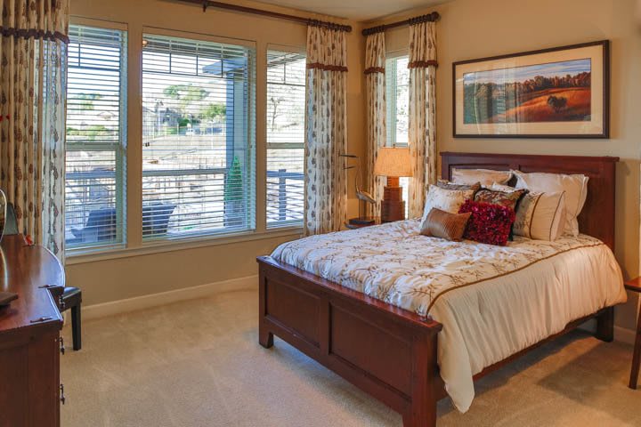 A cozy and well-decorated bedroom with large windows and warm lighting.