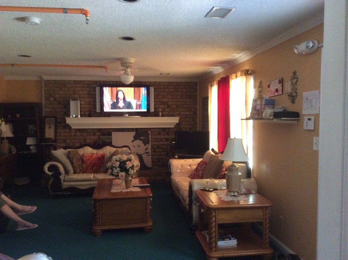 A cozy living room with sofas, a coffee table, and a television above the fireplace.