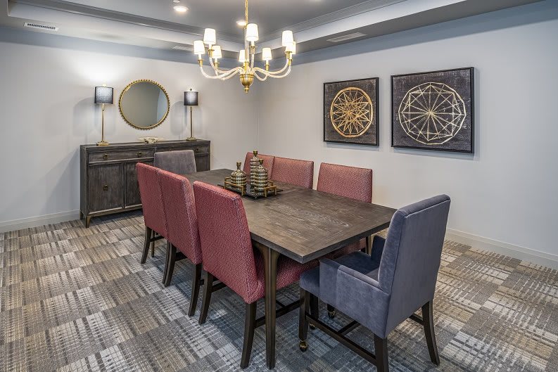 A modern dining room with upholstered chairs and elegant chandelier.